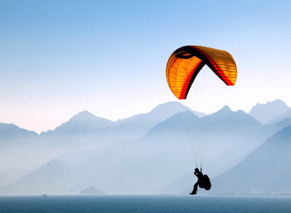 person paragliding with mountains in the background
