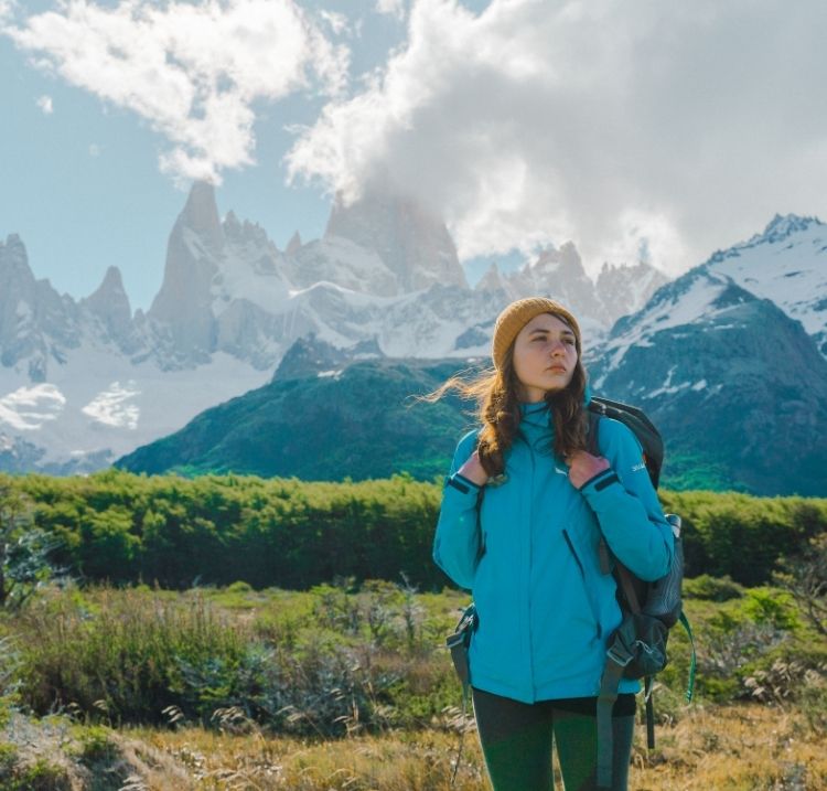girl with blue jack hiking through the mountains at Argentina