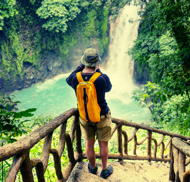 a traveler taking a photo of a beautiful waterfall from a stairwell