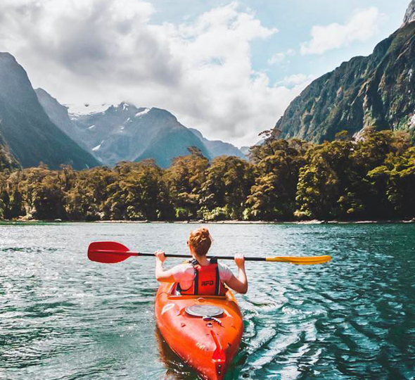 a woman kayaking with mountains in the background