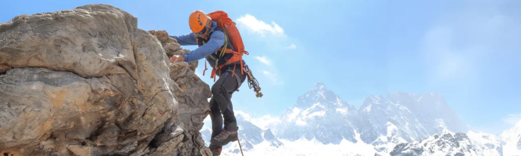 a man scaling down a mountain rock