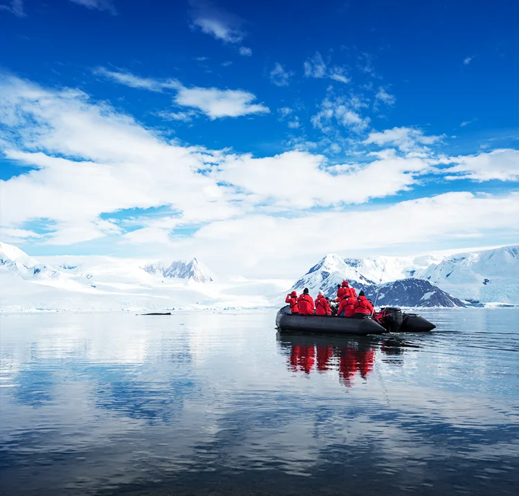 Tourists in orange parkas in a small float boat touring the Antartica glaciers